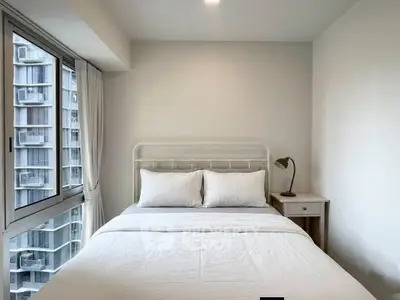 Cozy bedroom with large window offering city view in modern apartment