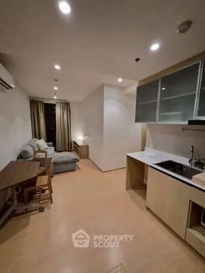 Modern open-layout living room with kitchen, featuring sleek design and cozy ambiance.