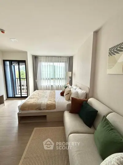 Modern bedroom with cozy decor and large window offering natural light