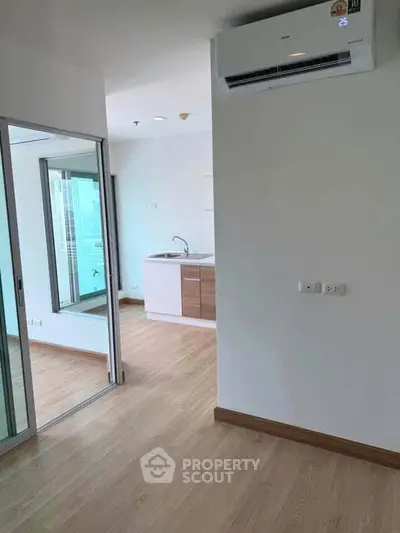 Modern apartment interior with sleek kitchen and air conditioning, featuring wooden flooring and bright natural light.