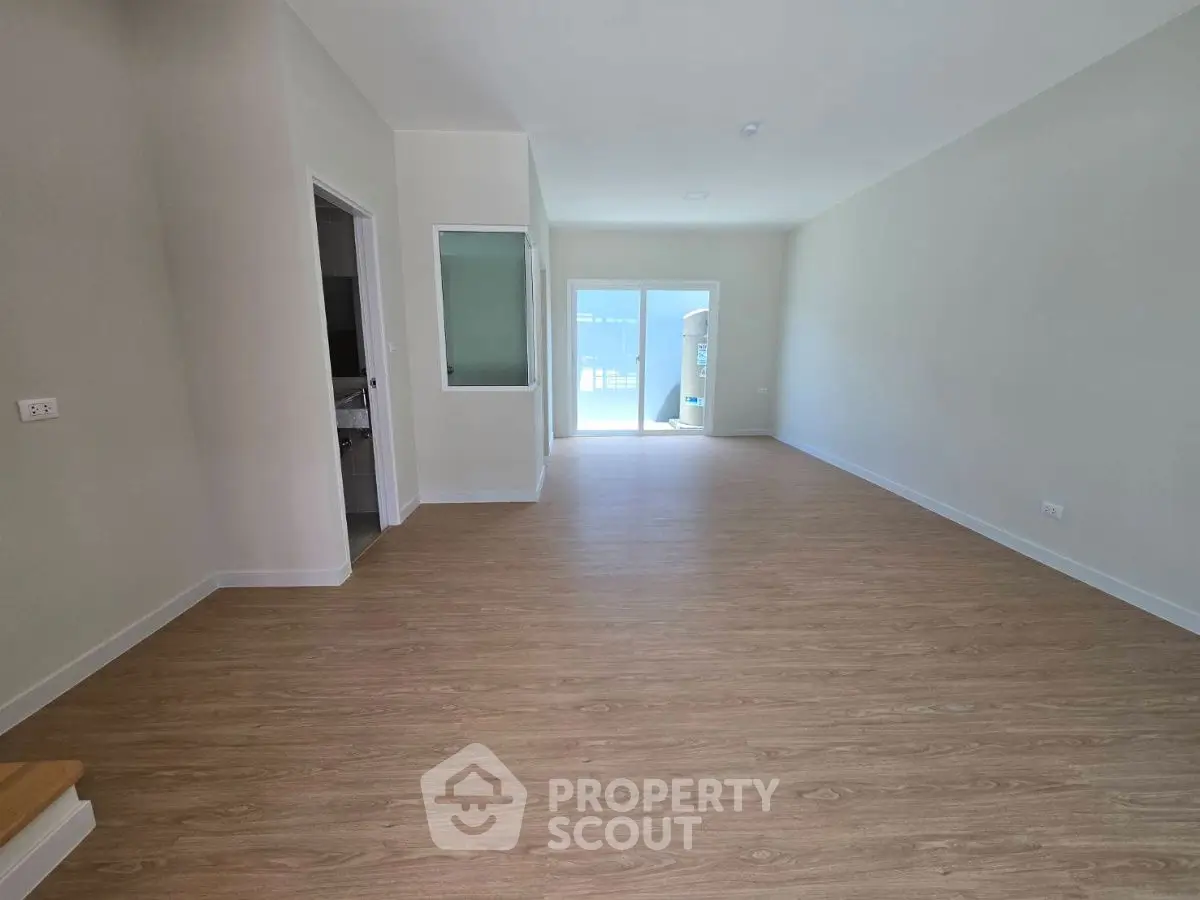 Spacious open-plan living area with wooden flooring and large windows for natural light.