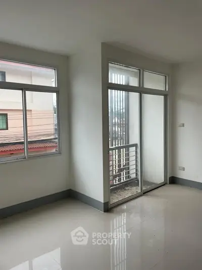 Bright empty room with large windows and balcony access, perfect for customization.