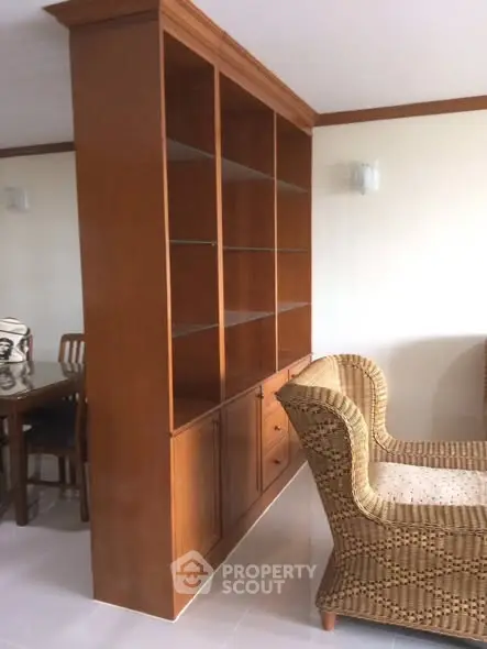 Spacious living room with elegant wooden shelving and cozy wicker seating, perfect for stylish home decor.