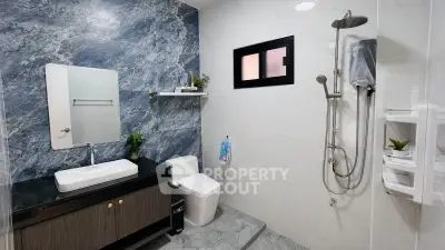 Modern bathroom with sleek design, featuring a rain shower, elegant vanity, and stylish wall tiles.