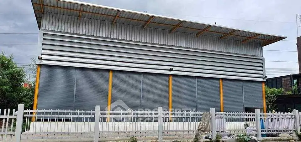 Modern industrial warehouse with large metal facade and secure fencing