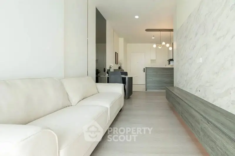 Modern living room with sleek design and open layout, featuring a comfortable sofa and stylish lighting.