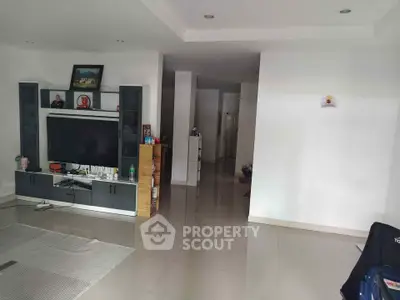 Spacious living room with modern entertainment center and sleek tile flooring.