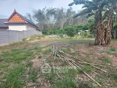 Spacious land plot with lush greenery and potential for development, featuring a traditional-style building nearby.