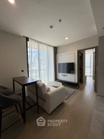 Modern living room with sleek design and natural light, featuring a cozy armchair and wall-mounted TV.