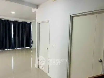 Spacious modern interior with sleek tiled flooring and elegant dark curtains, perfect for stylish living.