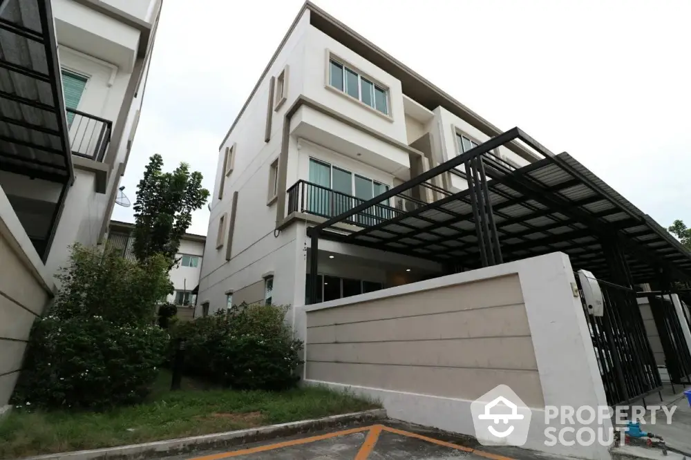 Modern townhouse exterior with sleek design and spacious balcony in a suburban neighborhood.