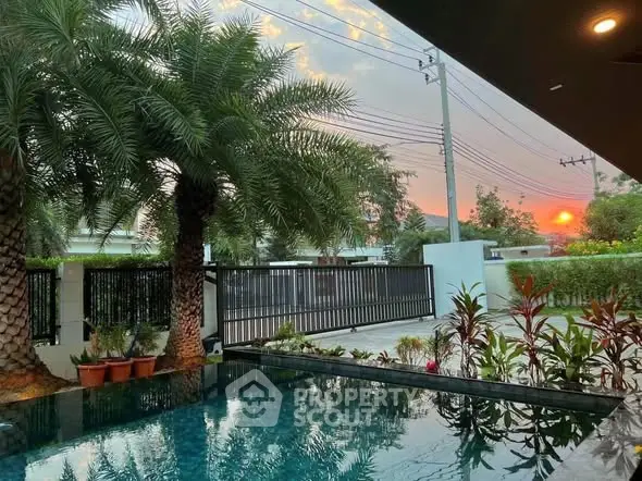 Luxurious poolside view with sunset and lush greenery in a serene residential setting.
