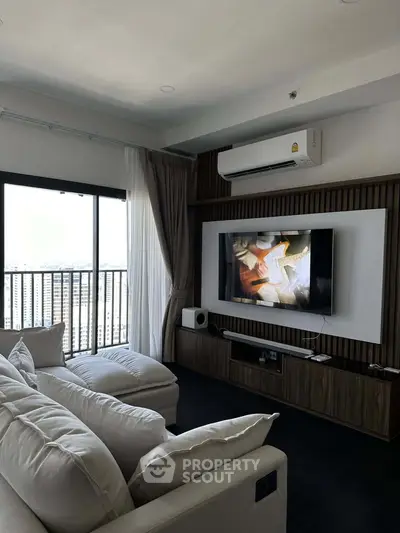 Modern living room with large TV, cozy sofa, and balcony view in a stylish apartment.