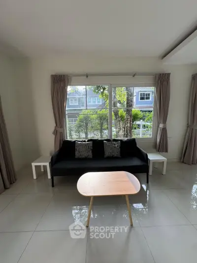 Spacious living room with modern sofa and large window offering garden view