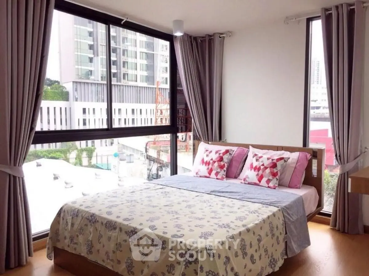Spacious bedroom with large windows and city view in modern apartment