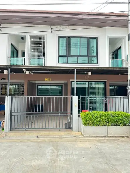 Modern two-story townhouse with sleek design and gated entrance, perfect for urban living.