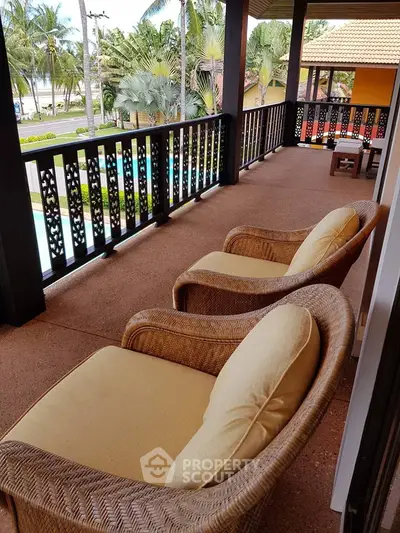 Spacious balcony with cozy seating and lush garden view in tropical setting.