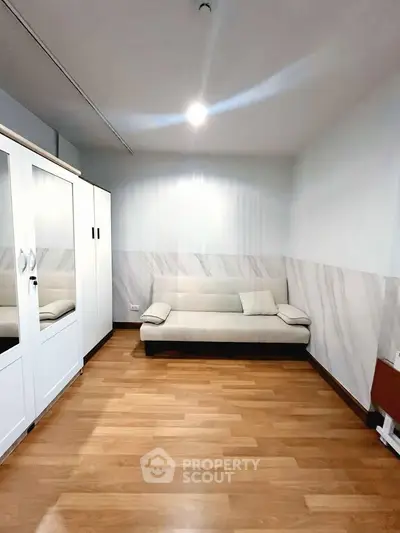 Spacious room with modern sofa and wooden flooring, ideal for cozy living.