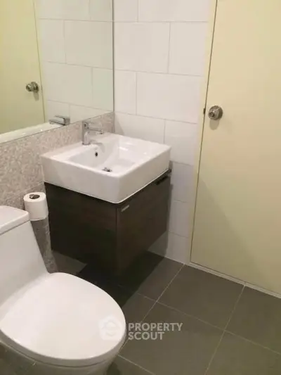 Modern bathroom with sleek fixtures and minimalist design, featuring a wall-mounted sink and toilet.