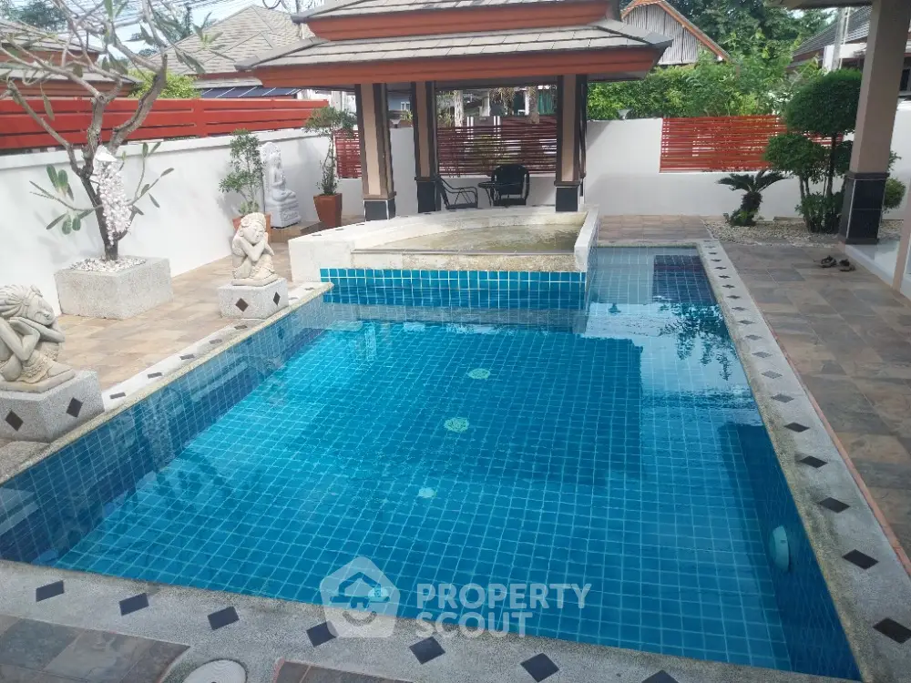 Luxurious outdoor pool with elegant stone statues and serene garden setting