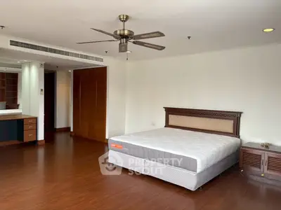 Spacious bedroom with wooden flooring and ceiling fan in modern apartment