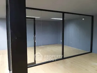 Modern office space with glass partitions and wooden flooring, ideal for a professional work environment.
