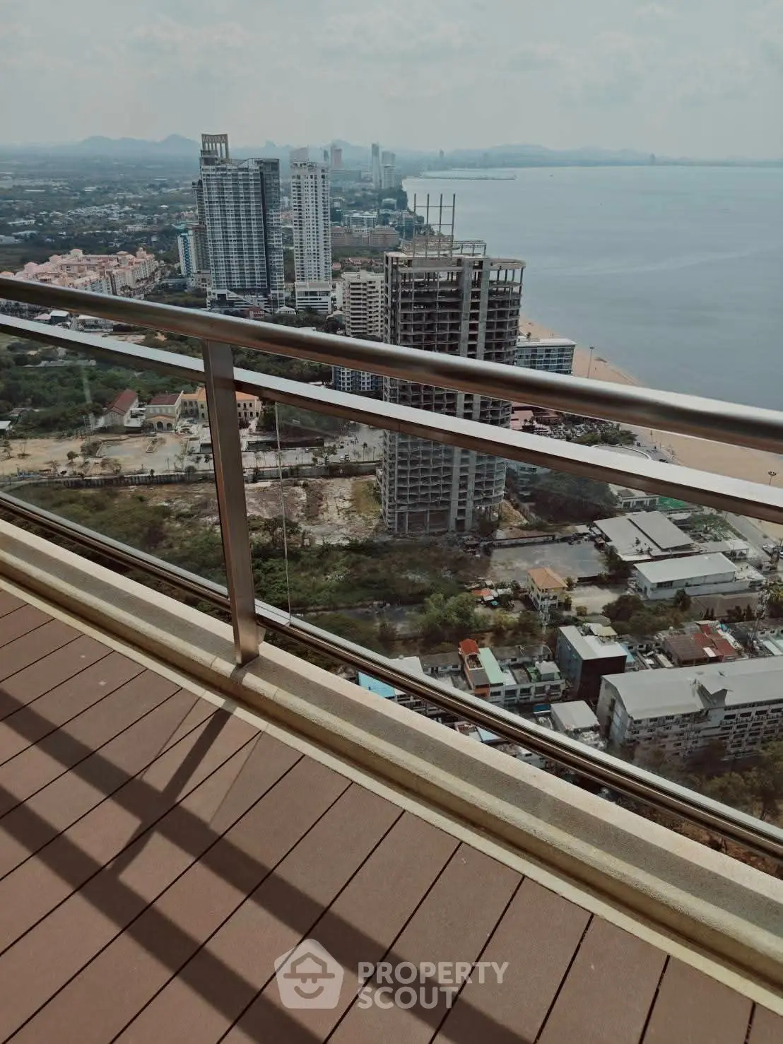 Stunning high-rise balcony view overlooking cityscape and ocean, perfect for urban living enthusiasts.