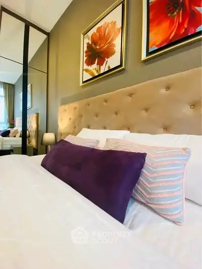 Luxurious bedroom with plush headboard and vibrant floral artwork, perfect for relaxation.