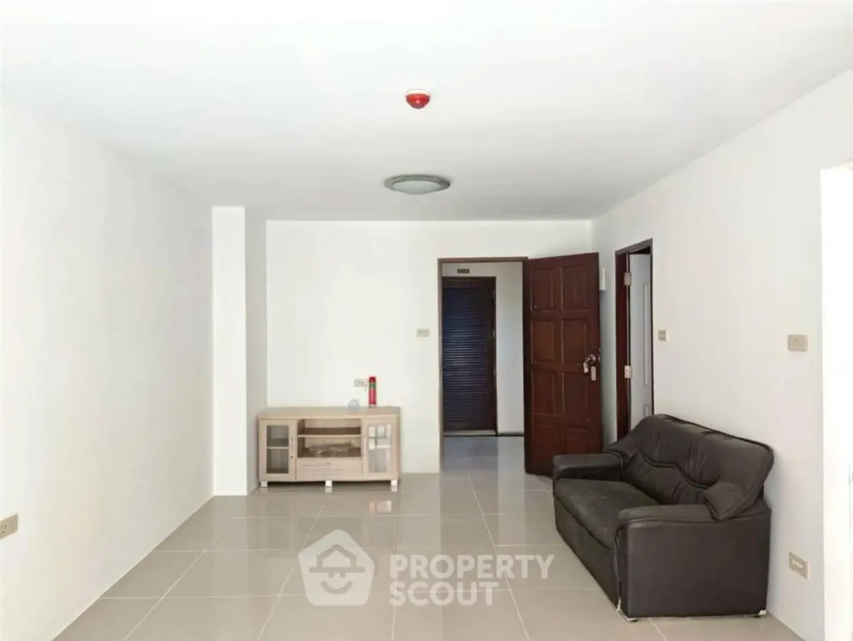 Spacious living room with modern tile flooring and minimalistic furniture in a bright apartment.
