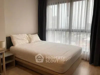 Cozy bedroom with large window offering city view, featuring a comfortable bed and modern decor.