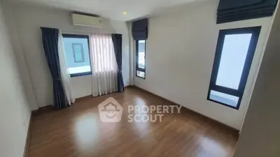 Spacious empty room with wooden flooring and large windows, perfect for customization.
