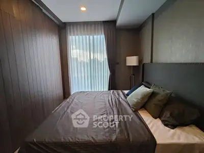 Modern bedroom with stylish decor and large window offering natural light.