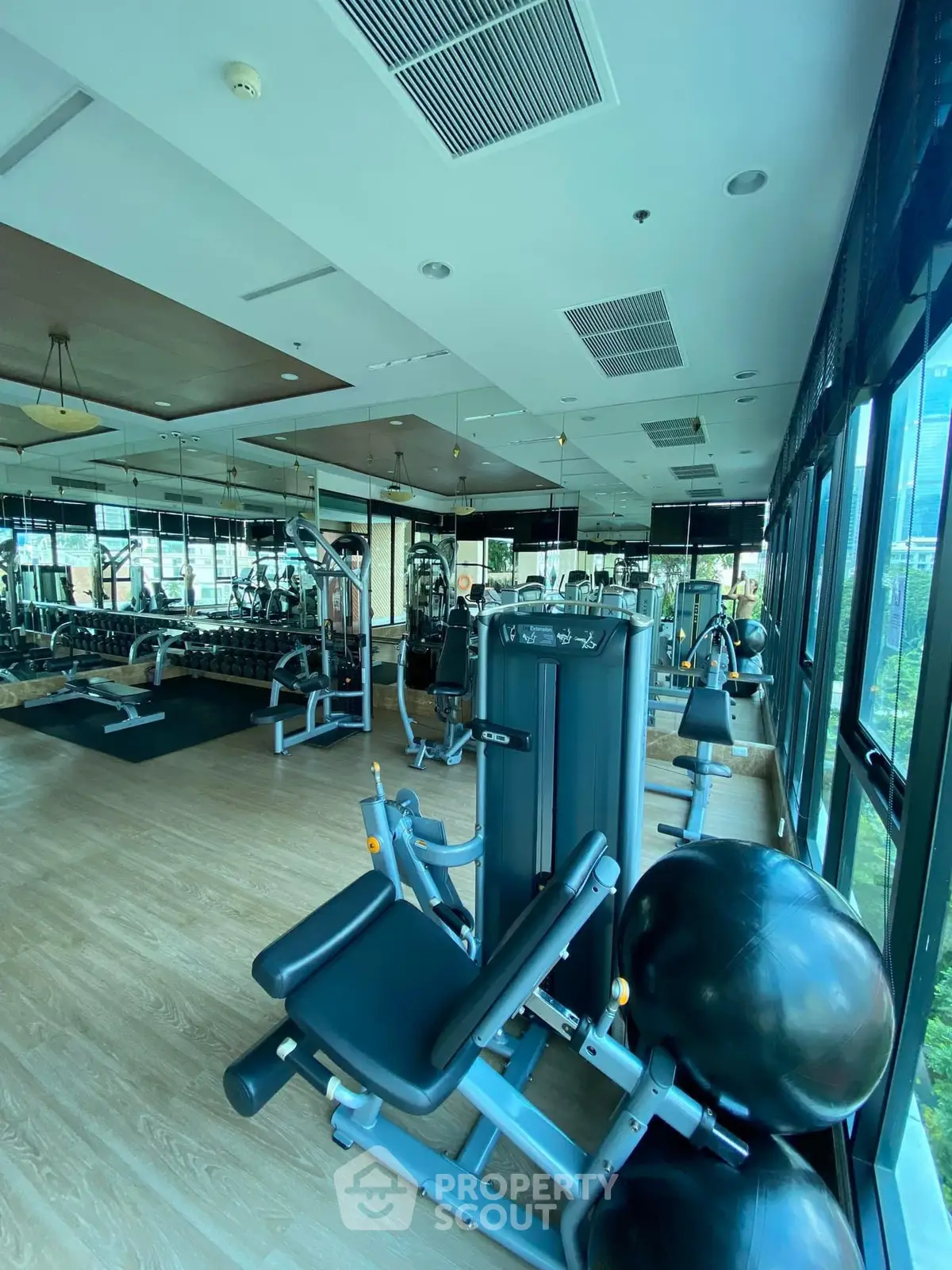 Spacious modern gym with state-of-the-art equipment and large windows offering natural light.
