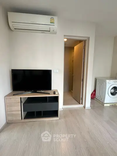 Modern living room with TV, air conditioner, and washing machine in a cozy apartment.