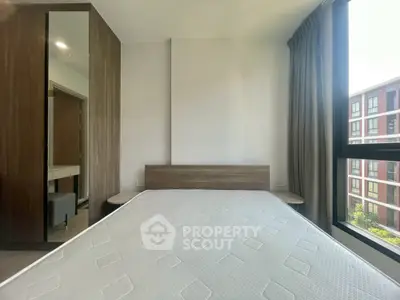 Modern bedroom with large window and wooden accents in a stylish apartment.