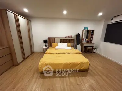 Spacious modern bedroom with wooden flooring and stylish furniture