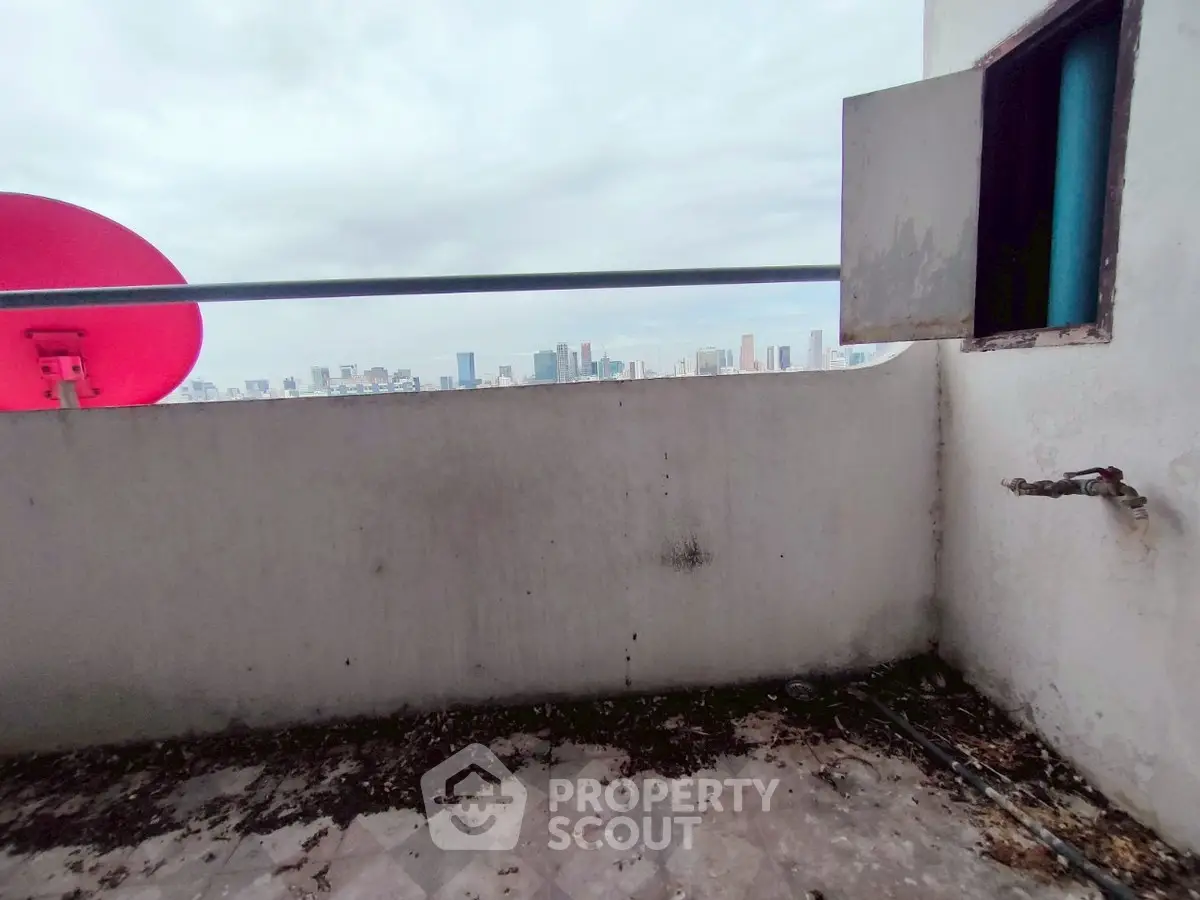 Urban balcony with city skyline view, featuring a satellite dish and outdoor faucet, ideal for renovation.