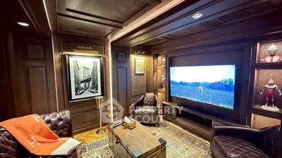 Luxurious home theater with leather seating and large TV in elegant wood-paneled room.