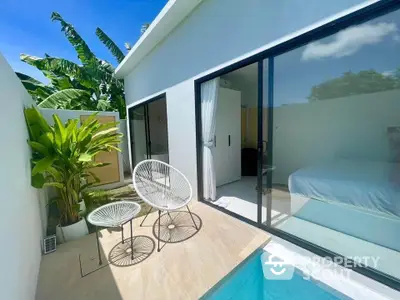 Modern villa with private pool and lush garden, featuring sleek sliding glass doors and stylish outdoor seating.