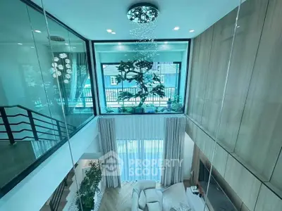 Luxurious modern living room with high ceiling and large windows offering stunning natural light.