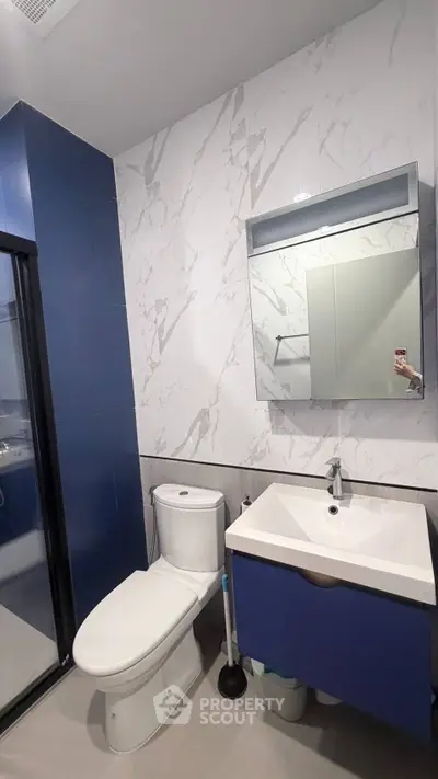 Modern bathroom with sleek blue and white design, featuring a stylish vanity and spacious shower area.