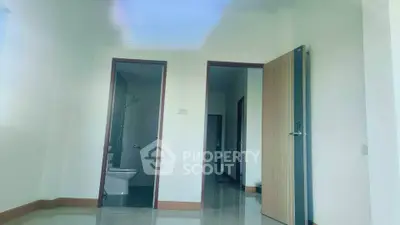 Spacious interior with modern bathroom and open door, showcasing sleek design.