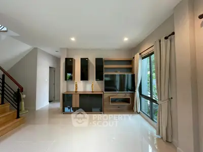 Modern living room with sleek TV unit and large windows for natural light.