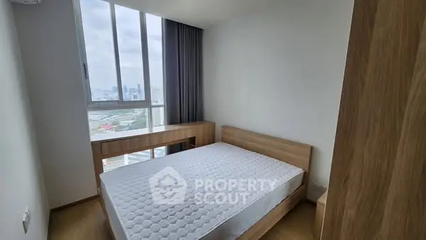 Modern bedroom with large window and wooden furniture, offering a serene city view.
