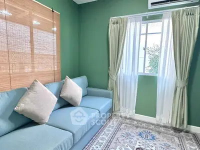 Charming living room with green walls, cozy blue sofa, and elegant curtains for a serene ambiance.