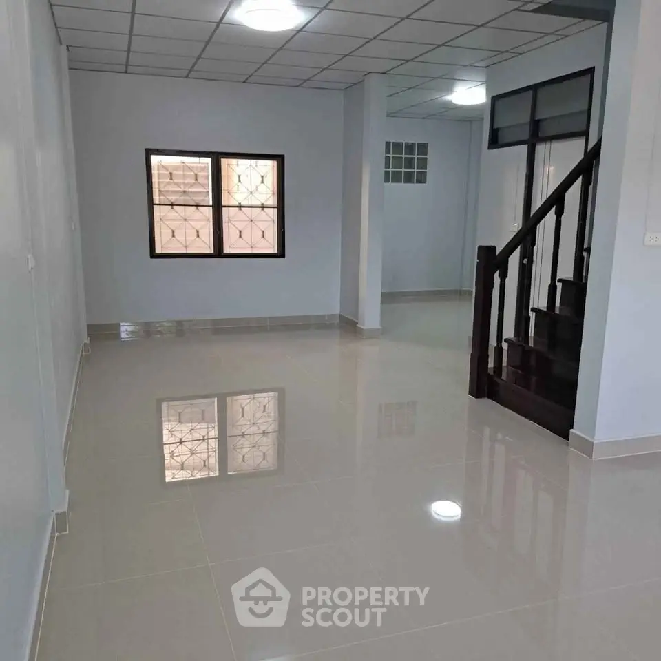 Spacious interior with glossy tiled floors and staircase, perfect for modern living.