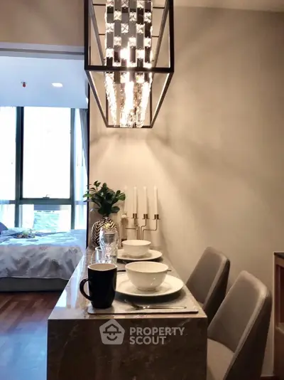 Modern dining area with elegant chandelier and cozy bedroom view.