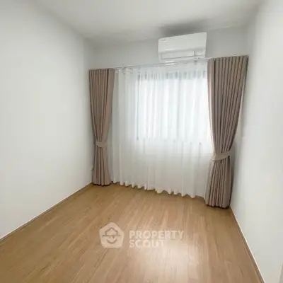 Minimalist bedroom with wooden flooring and large window with curtains.