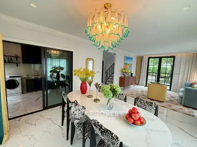 Luxurious open-plan living and dining area with elegant chandelier and modern decor.
