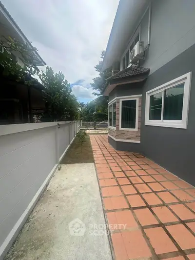 Charming suburban home exterior with tiled pathway and lush greenery, perfect for family living.